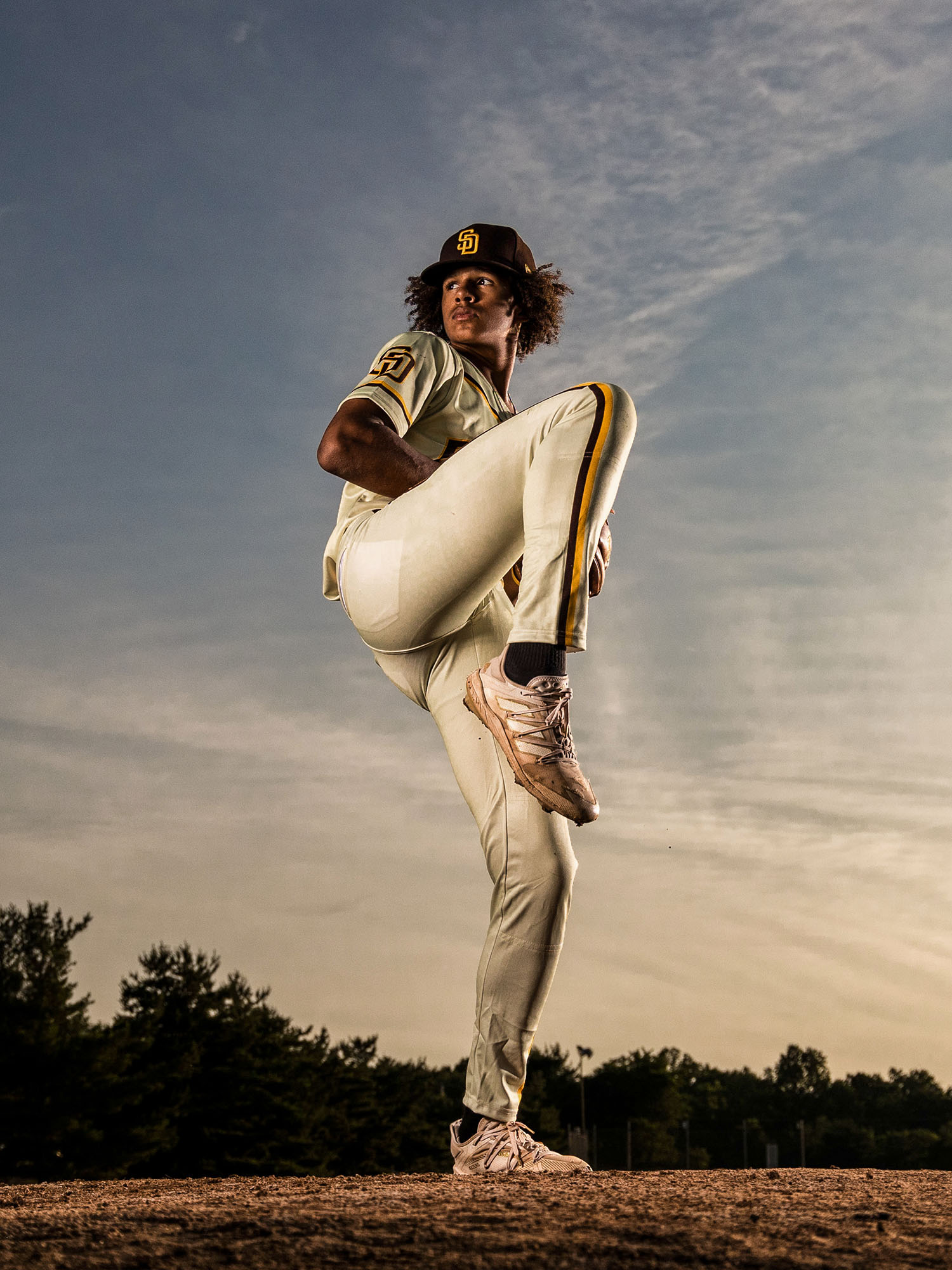 Delaware Sports Portrait Photographer | Image of a tall pitcher winding up for a pitch at sunset.