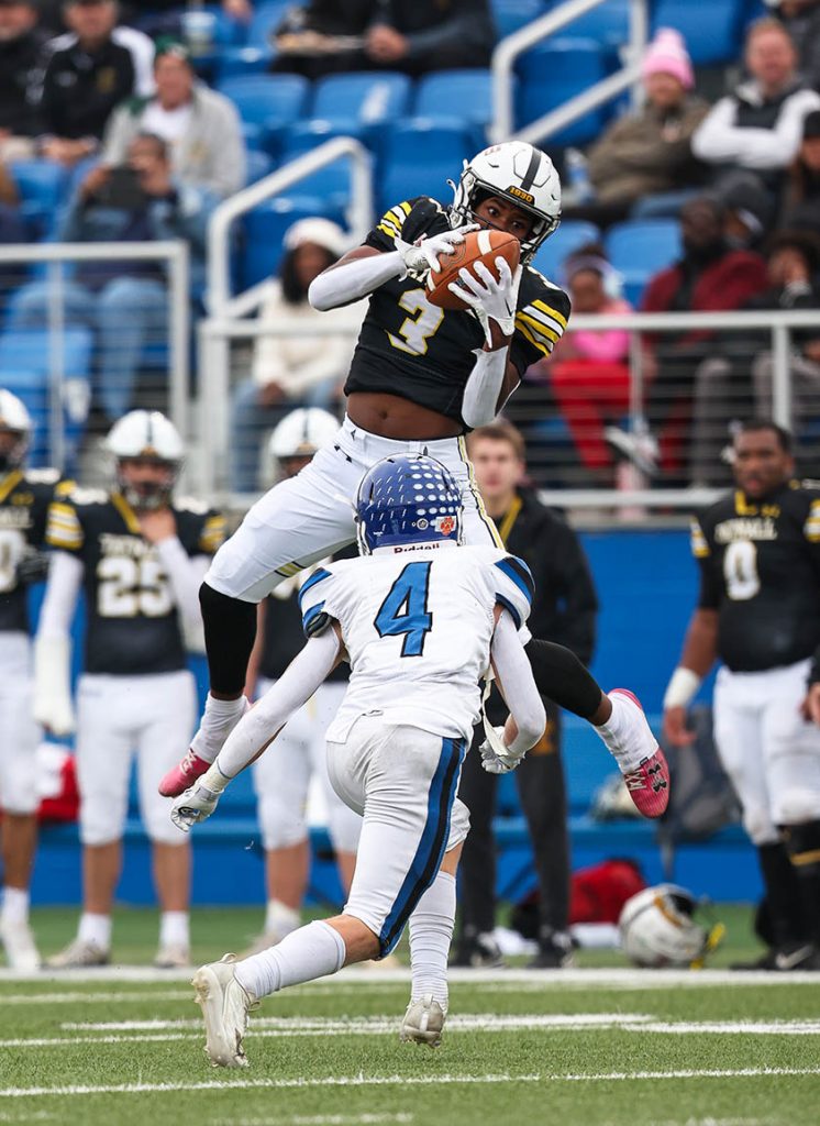 A high school football receiver leaps to grab a pass while a defensive back pursues. Delaware Sports Photographer. Delaware Portrait Photographer. Andre El Photography